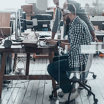Zwei Männer arbeiten konzentriert an Computern in einem modernen Büro.
